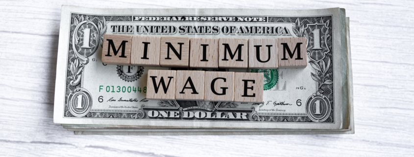 Minimum wage word written on wood block with American Dollar-bills.