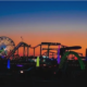 an amusement park with a ferris wheel at sunset