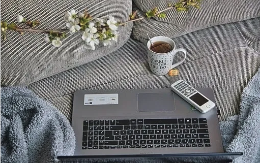 a laptop computer sitting on top of a couch next to a cup of coffee