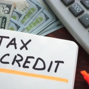 a notepad with the words tax credit on it next to a calculator