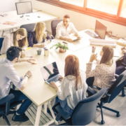 a group of people sitting around a table with laptops